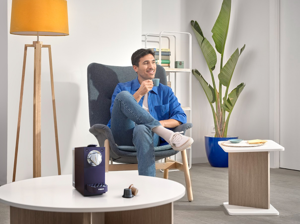 Adulto varón sentado tomando un café servido por la cafetera de Aquaservice.